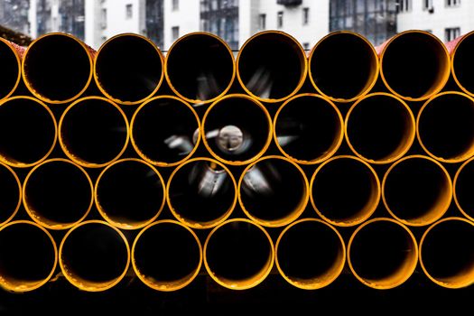 Pile of round industrial material polyethylene thermoplastic pipes on a construction site.