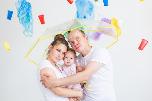 Problem of trash, plastic recycling, pollution and environmental concept - Sad family hiding from garbage under an umbrella on white background.