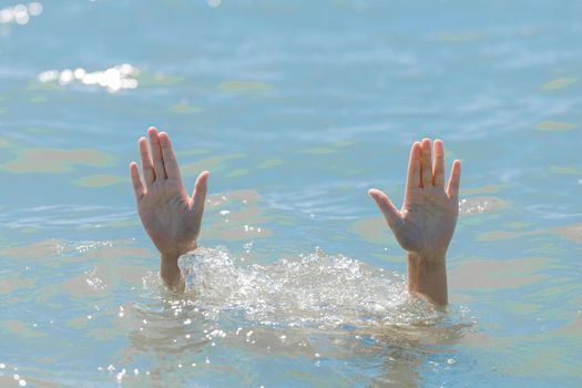 A hands from under the water of a drowning girl, help and urgent rescue of a person during a dangerous swimming, sos.