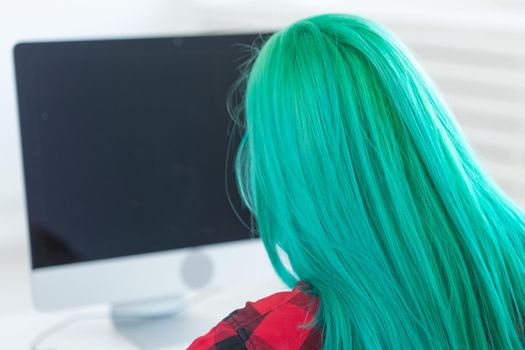 Work, business, style, people concept - perspective from behind of woman with green hair working at the laptop.