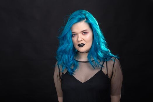 Style and fashion concept - Young and attractive woman with blue hair posing over black background.