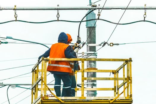 Two working men raised safety on a machine crane equipment mending a power electric line.