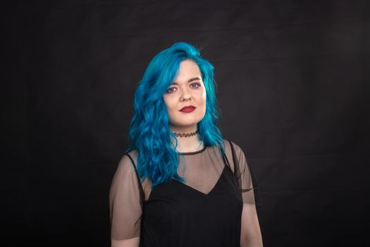 Style and fashion concept - Young and attractive woman with blue hair posing over black background.