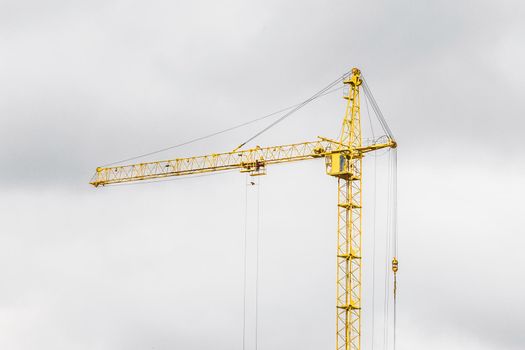 Tower construction building yellow industrial crane against the grey sky.