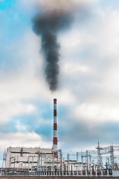 Environmental problem, environmental pollution, smoke from the pipe of an thermal power plant against a blue sky.