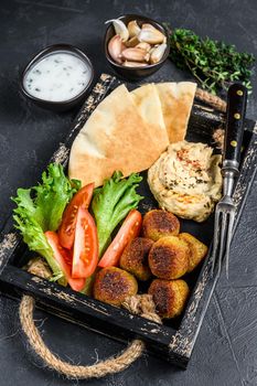 Traditional homemade Hummus chickpea, falafel, pita bread and fresh vegetables. Black background. Top view.