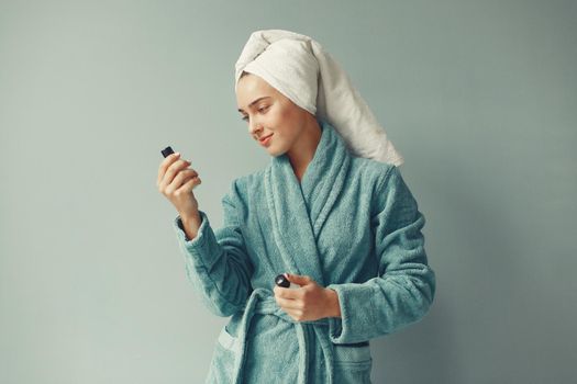 Girl in a studio. Lady with cream. Woman in a blue bathrobe