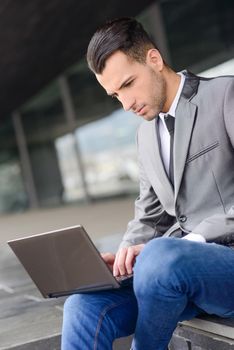 Portrait of attractive young businessman typing in a laptop computer in office building