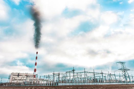 Environmental problem, environmental pollution, smoke from the pipe of an thermal power plant against a blue sky.