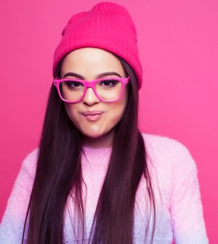 young pretty girl with brunette long hair posing cheerful on pink background, lifestyle people concept close up