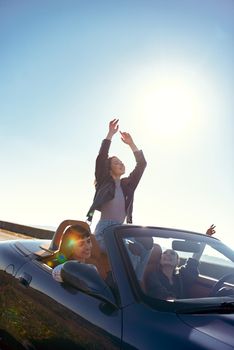 Portrait of three pretty young women driving on road trip on beautiful summer day.