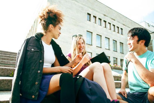 cute group of teenages at the building of university with books huggings, diversity nations, having lunch closeup