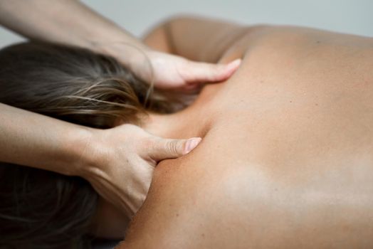 Young woman receiving a back massage in a spa center. Female patient is receiving treatment by professional therapist.