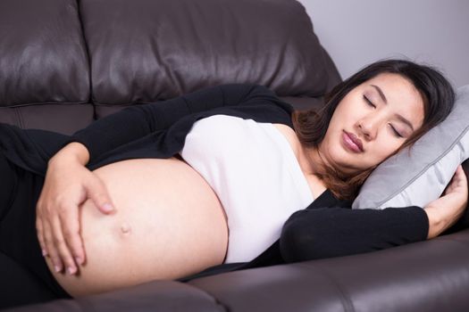 Pregnant woman sleeping on sofa in home