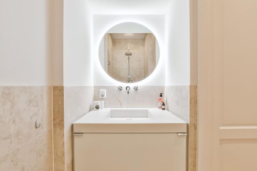White washbasin with a round beautiful mirror with lighting