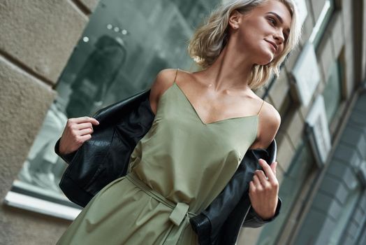 Fashion. Young stylish woman walking on the city street taking off jeans jacket smiling joyful close-up