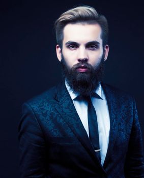 portrait of young bearded hipster guy on gray dark background close up, brutal modern man in suit, lifestyle people concept close up