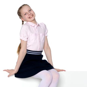 Beautiful schoolgirl girl with long pigtails sitting on the couch. The concept of school fashion, children's emotions. Isolated on white background.