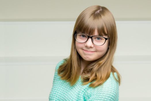 Beautiful schoolgirl girl in glasses sits on a white staircase. The concept of happy people, childhood.