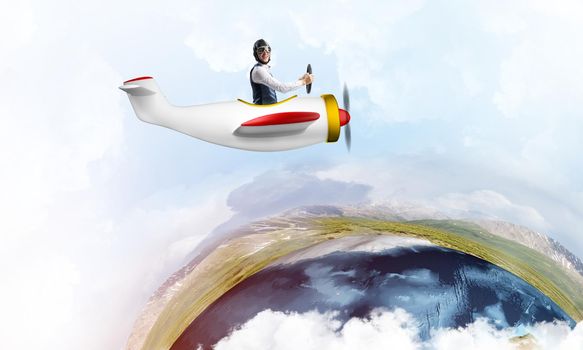 Aviator in leather helmet driving small propeller plane in cloudy blue sky. Extreme aviation hobby and free time activity. Funny man flying in small airplane. Earth globe horizon with sea line