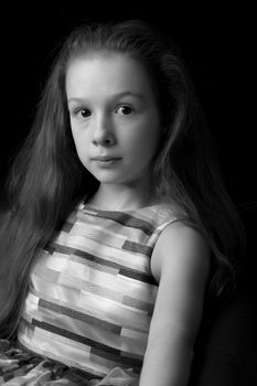 Beautiful little girl, studio portrait on a black background. The concept of a happy childhood, style and fashion.