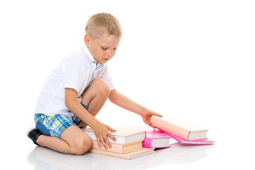 A cute little boy, a preschooler with books. The concept of education, the intellectual development of the child in the family. Isolated on white background.