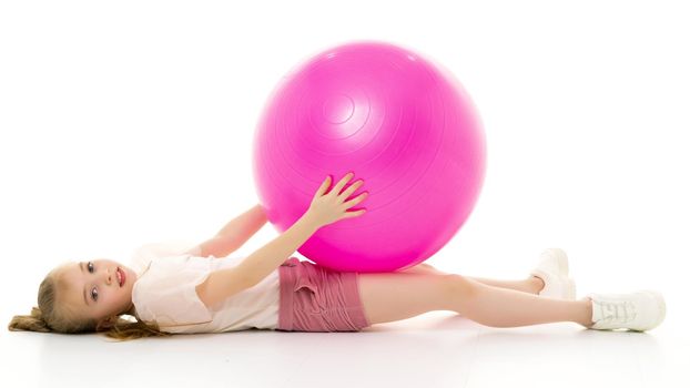 A charming little girl is engaged in fitness with a ball. The concept of gymnastics, health and sports. Isolated on white background.