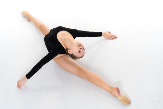 A little girl performs a gymnastic twine. The concept of fitness and sports. Isolated on white background.