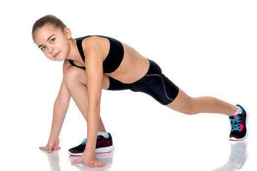 A girl gymnast performs an acrobatic element on the floor. The concept of childhood, sport, healthy lifestyle. Isolated on white background.