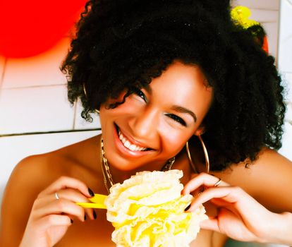 young afro-american teen girl laying in bath with foam, wearing swag jewelry flawless, making selfie close up