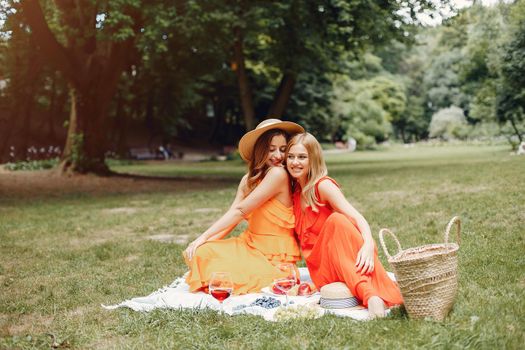 Beautiful girl in a red dress. Women sitting in a summer park.