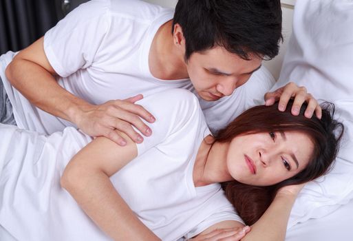 unhappy woman lying on bed with a concerned guy comforting her in the bedroom