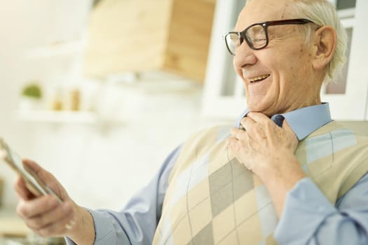 Joyous elderly man smiling and video-calling his general practitioner while staying at home