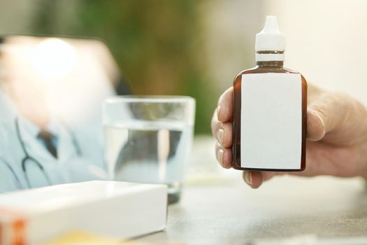 Copy-space photo of hand holding a tiny brown bottle of medication with a blank label