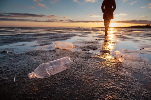 Plastic bottles thrown ashore and the man in the background. Environmental pollution by plastic. Recyclable packaging.