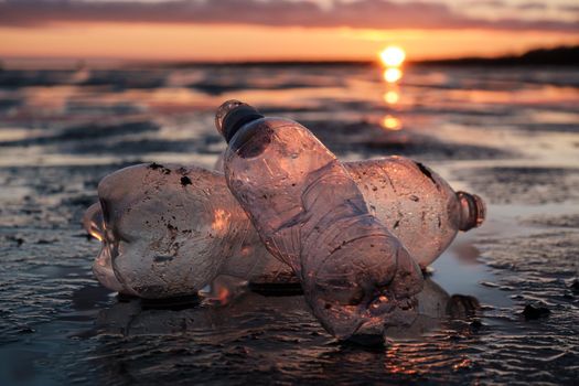 Close-up of plastic bottles thrown on the shore in the backlight. Environmental pollution by plastic. Recyclable packaging.