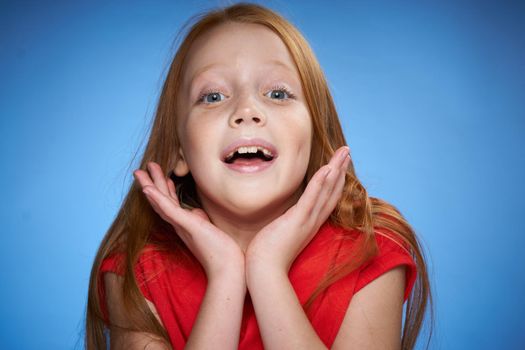 cute red-haired girl in red t-shirt emotions blue background. High quality photo