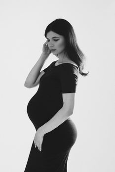 picture of a beautiful caucasian pregnant female touching her long hair, black and white picture isolated on white background