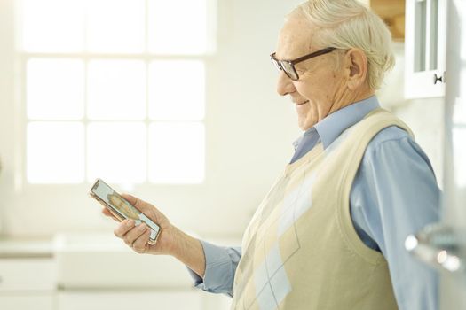Grey-haired senior citizen smiling while having a video call consultation with his doctor online