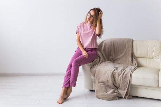 Young attractive woman dressed in beautiful colorful pajama posing as a model in her living room. Comfortable sleepwear, home relaxation and female fashion concept