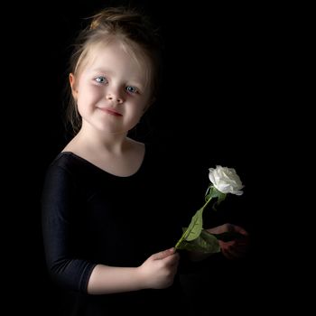 Beautiful little girl with a flower in her hand. The concept of style and fashion. On a black background.