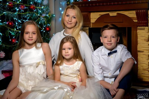 Happy young family with children at Christmas near a Christmas tree and a fireplace. The concept of holidays, winter, Christmas, Happy childhood, the harmonious development of children in the family.