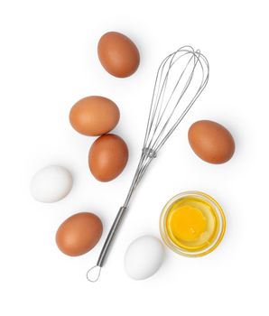 Fresh eggs with whisk isolated on white background, close up