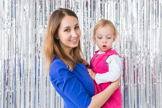 Childhood, holidays and family concept - Mother kissing baby daughter on shiny background. Close-up.