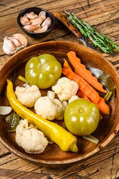 Salted and pickles vegetables preserve in a wooden plate. wooden background. Top view.