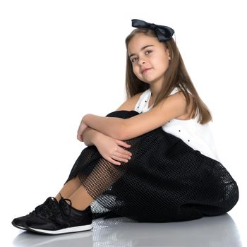 A beautiful teen girl sits on the floor on a white background. The concept of education and schoo. Isolated.