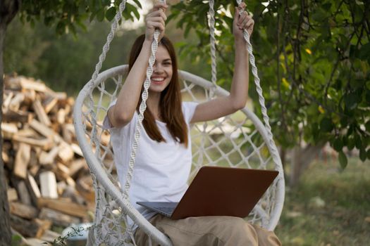 woman with laptop outdoors resting in hammock internet. High quality photo