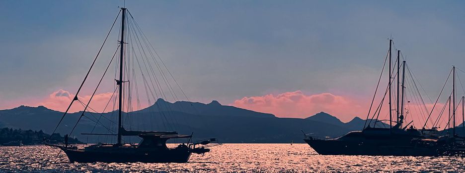 Tranquil seascape and coastal nature concept. Sea, boats, mountains and blue sky over horizon at sunset.