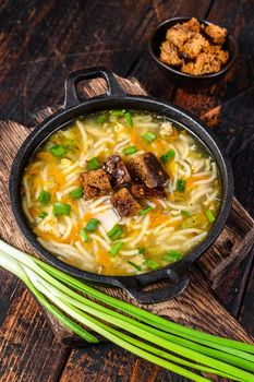 Chicken soup with noodles and vegetables. Dark wooden background. Top view.