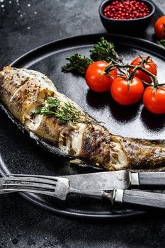 Baked pollock cooked in a savory marinade. Black background. Top view.